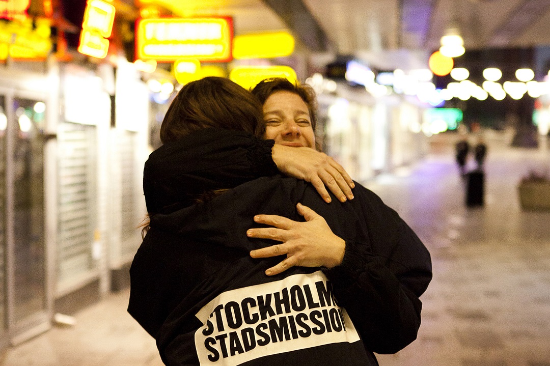 Två personer kramas, en person med Stockholms stadsmissions jacka
